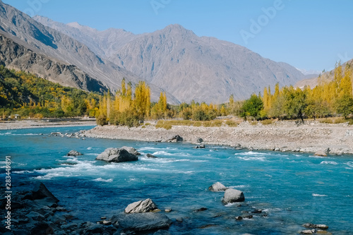 Clear turquoise blue water river flowing along Hindu Kush mountain range in Ghizer valley. Autumn scenery in Gilgit Baltistan, Pakistan.