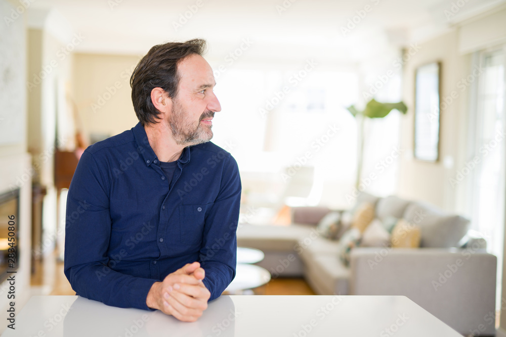 Handsome middle age man at home looking to side, relax profile pose with natural face with confident smile.