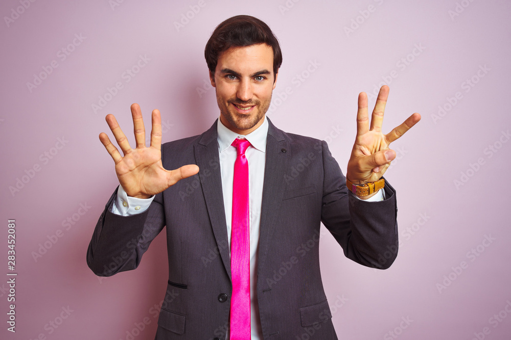 Young handsome businessman wearing suit and tie standing over isolated pink background showing and pointing up with fingers number eight while smiling confident and happy. Young handsome businessman wearing suit and tie standing over isolated pink background showing and pointing up with fingers number eight while smiling confident and happy.