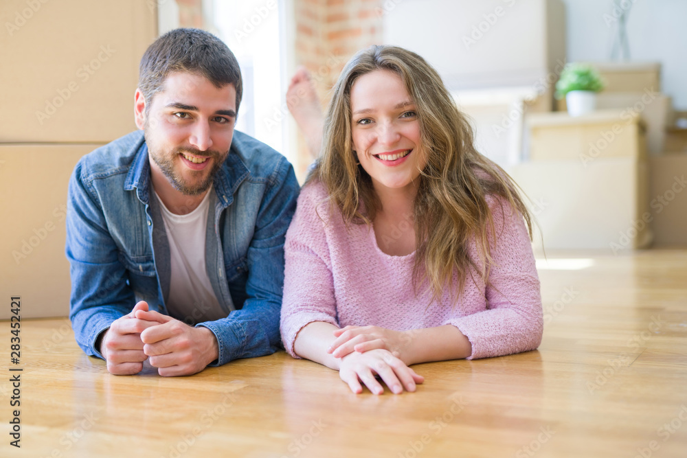 Young beautiful couple in love relaxing lying on the floor together with cardboard boxes around for moving to a new house Young beautiful couple in love relaxing lying on the floor together with cardboard boxes around for moving to a new house