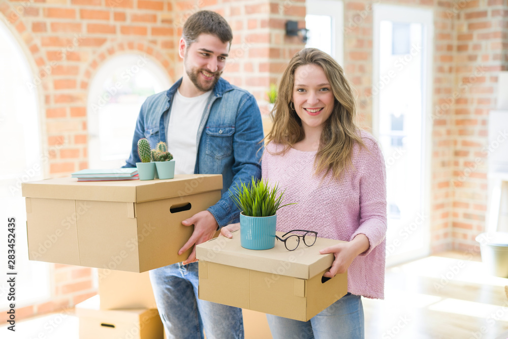 Young beautiful couple very happy together holding cardboard boxes moving to a new home Young beautiful couple very happy together holding cardboard boxes moving to a new home