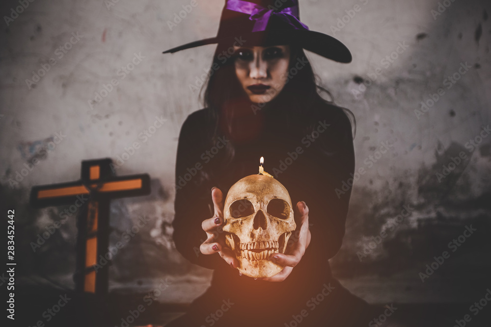 Fototapeta Halloweenowy pojęcie - Czarownicy kobieta trzyma duch czaszkę, Tajemnicza demon dziewczyna z czerwonymi wargami. Wampir Witch Lady z krwi w ustach na czarnym tle.