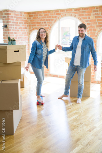 Young couple moving to a new home, having fun riding a skateboard at new apartment around cardboard boxes © Krakenimages.com