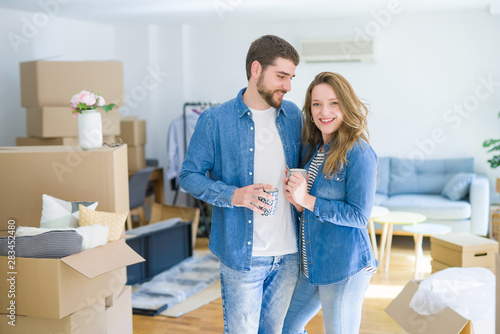 Young couple relaxing from moving to a new house drinking a coffee around cardboard boxes © Krakenimages.com
