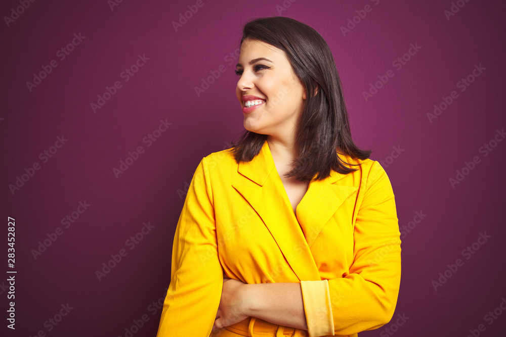 Young beautiful brunette woman wearing elegant yellow jacket over purple isolated background looking away to side with smile on face, natural expression. Laughing confident. Young beautiful brunette woman wearing elegant yellow jacket over purple isolated background looking away to side with smile on face, natural expression. Laughing confident.