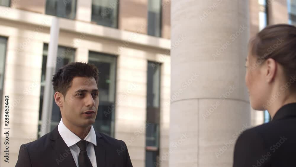 Back view of two diverse business people standing outdoors and talking Back view of two diverse business people standing outdoors and talking