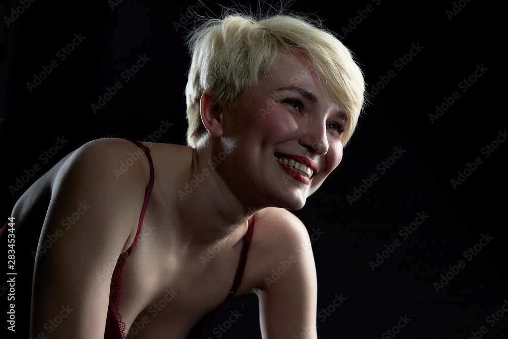 Sexy blonde girl during professional photo shoot in dark room. Model in a red swimsuit Sexy blonde girl during professional photo shoot in dark room. Model in a red swimsuit