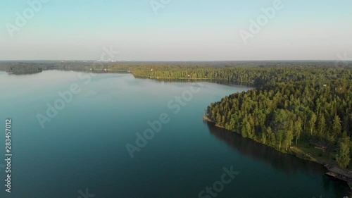 Aerial, drone shot, overlooking forest and tranquil waters,on the coast of lake Hvittrask, on a sunny, summer evening, in Kirkkonummi, Uusimaa, Finland photo