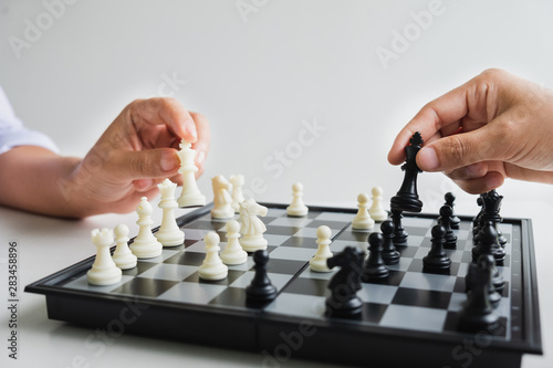 hand of businessman moving chess in competition, shows leadership, followers and business success strategies