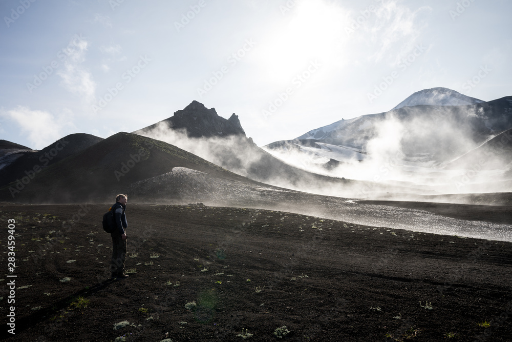 Misty magical morning in Avacha base camp. Kamchatka Peninsula, Russian far east. Mountain peaks and ribs of the volcano. Clouds creating mystical landscape. Direct sun through veil of fog