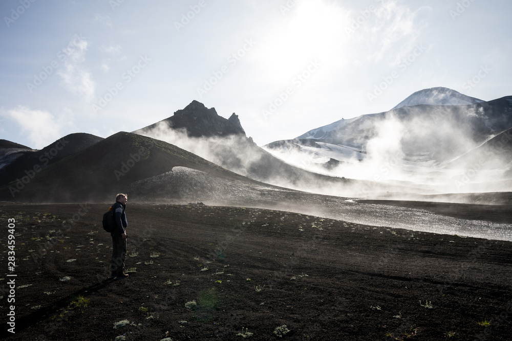 Fototapeta premium Misty magical morning in Avacha base camp. Kamchatka Peninsula, Russian far east. Mountain peaks and ribs of the volcano. Clouds creating mystical landscape. Direct sun through veil of fog