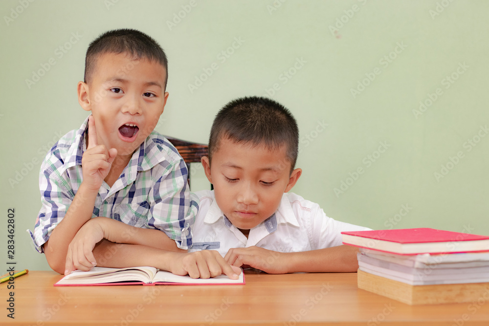 Two boys, reading a book, educating themselves Two boys, reading a book, educating themselves