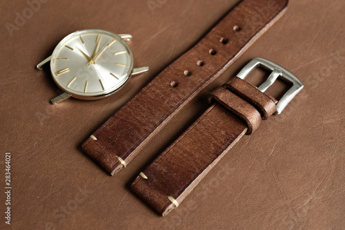 Dark brown leather watch strap with stainless buckle on leather background, Craft and handmade watch bracelet, Luxury classic and vintage style.