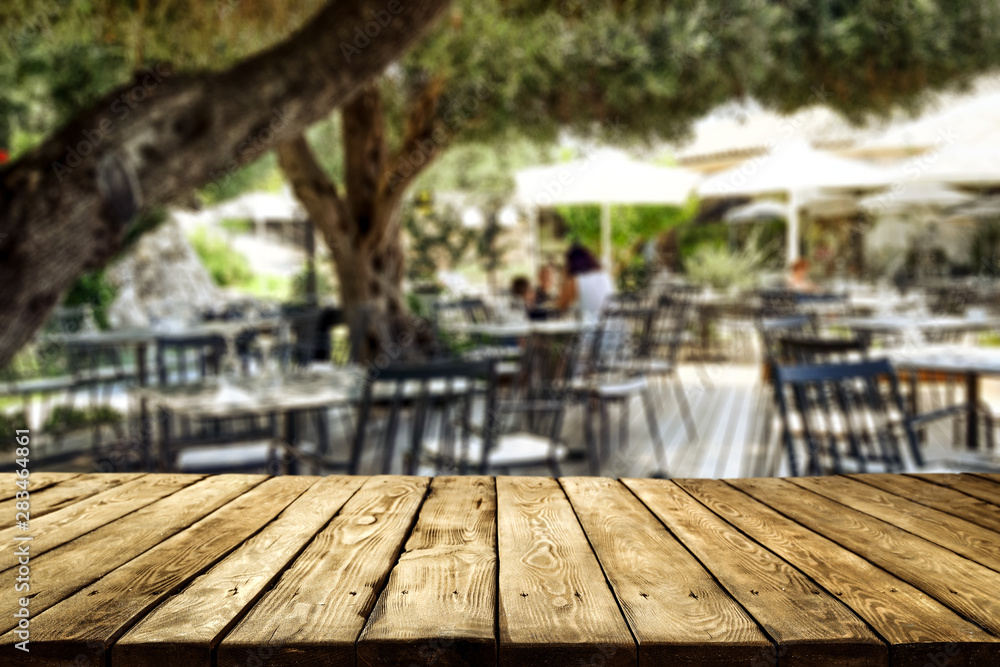 Table background and restaurant outside on sunny day in distance. Empty space for products and decoration. Table background and restaurant outside on sunny day in distance. Empty space for products and decoration.