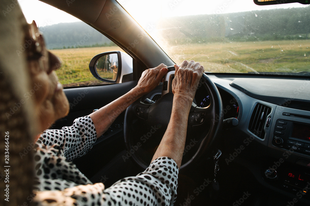 Old woman holds hands on wheel Stock Photo | Adobe Stock