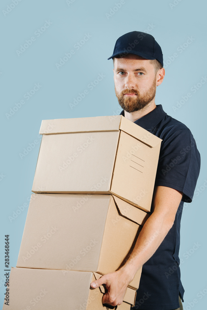 Delivery man in uniform is holding stack of cardboard boxes Delivery man in uniform is holding stack of cardboard boxes
