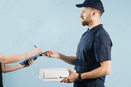 Woman hand accepting a box delivery from a courier, signing paper form with pen
