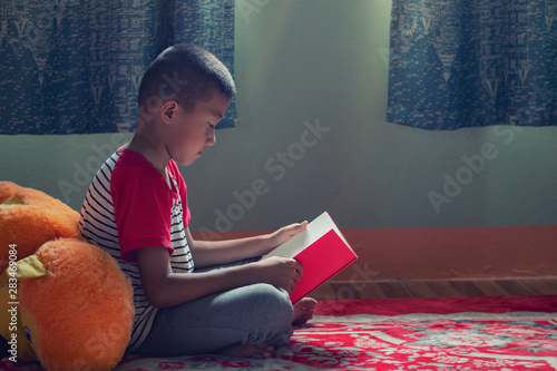Happy Asian boy reading story book.