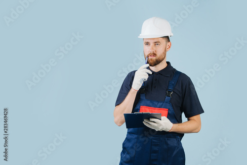 Construction engineer in a white helmet and blue uniform with a paper schematics
