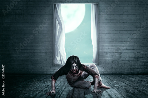 Scary zombies with blood and wound on his body crawling on the abandoned house