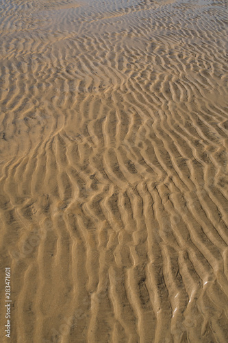 Footprints left in the sand of the beach by the waves when the tide is low.