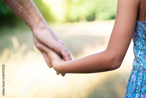 Man's and kid's hands. Father leads his child, summer nature outdoor. Parenting, togetherness, help, union, childhood, trust, family concept. © Khorzhevska
