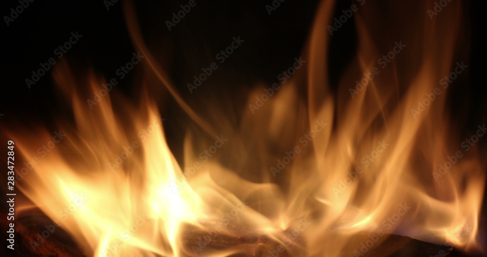 Campfire In The Night. Burning logs in orange flames close up. Background of the fire. Beautiful fire burns brightly. Embers of the fire climb up. Red flames surging up. Campfire In The Night. Burning logs in orange flames close up. Background of the fire. Beautiful fire burns brightly. Embers of the fire climb up. Red flames surging up.