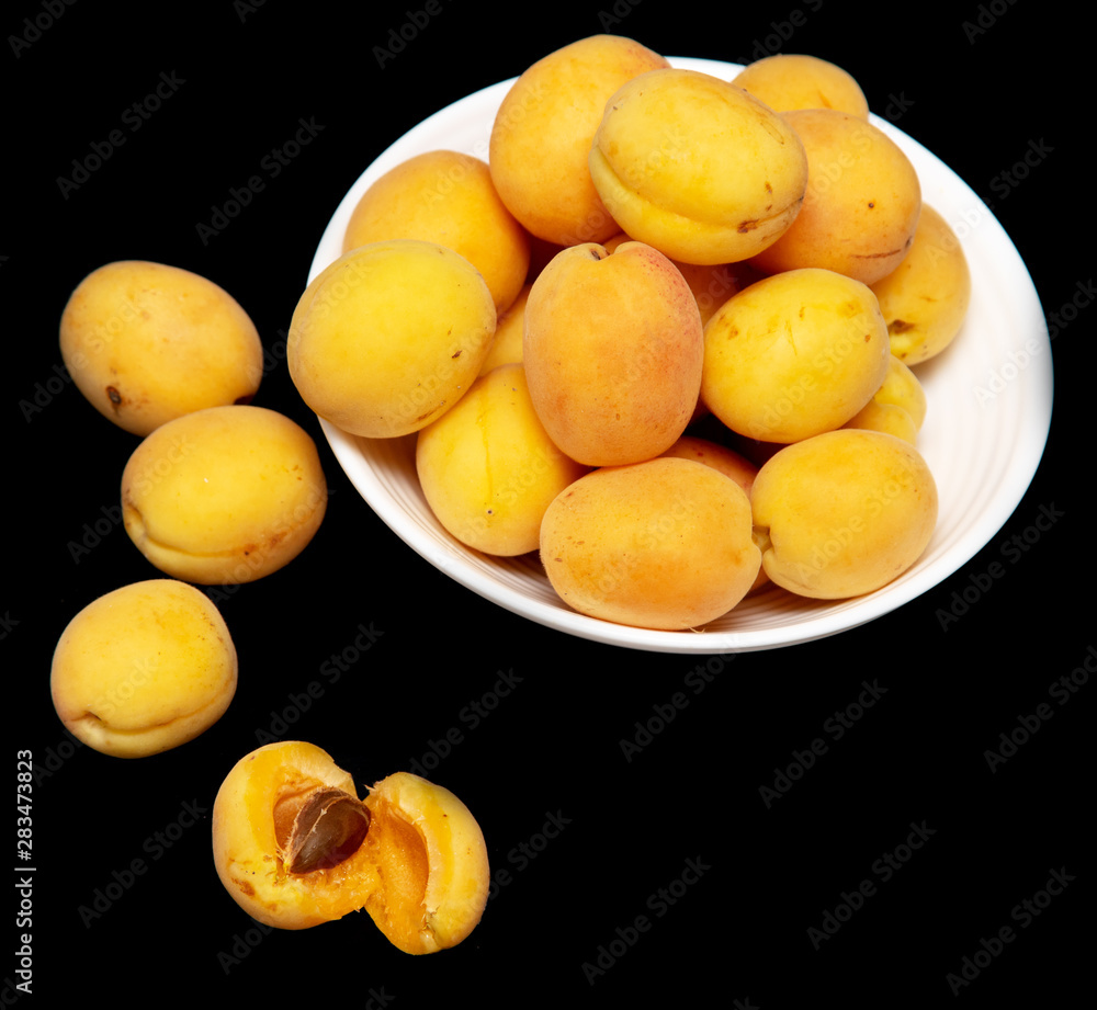 Ripe apricot in a white plate on a black background Ripe apricot in a white plate on a black background