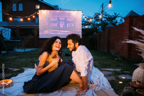 Couple in love is spending time together on the lawn in a courtyard in twilight