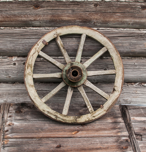 Old wooden log wall with a wooden wheel from the old carts © Anatoly