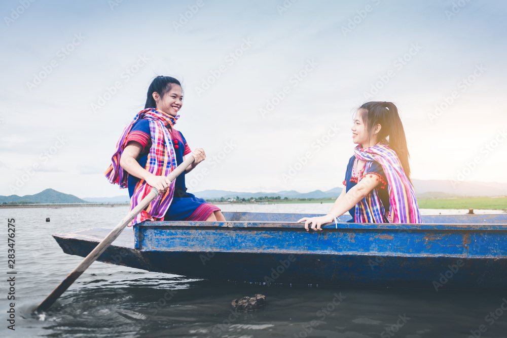 Obraz premium Beautiful Asian girls on fishing boat in lake to catch fish at countryside of Thailand