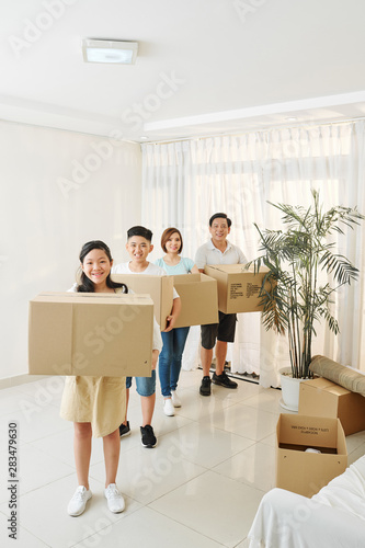 Parent and children holding cardboard boxes with belongings packed for house move