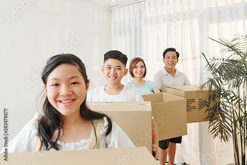 Smiling Vietnamese family members with cardbord boxes standing one behind another and looking at camera photo