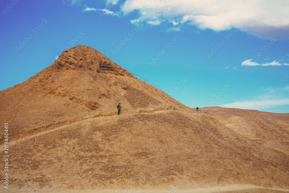 Desert landscape. A man stands on a hill. Climbing Masada from the west