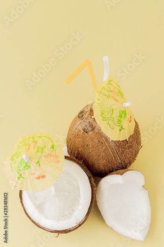 Fresh Coconut cocktail with a straws on yellow background, copy space