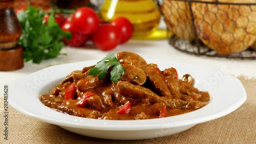 Boeuf, Stroganow, Strogonow. Classic, Russian beef stew. Served on a white plate. Front view. Food presentation. Turning the platter. Decorating with a parsley leaf. photo