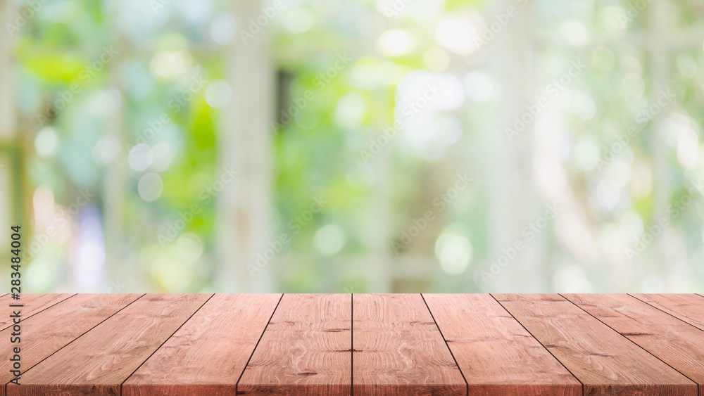 Empty wood table top and blurred of interior room with window view from green tree garden background background - can used for display or montage your products. Empty wood table top and blurred of interior room with window view from green tree garden background background - can used for display or montage your products.