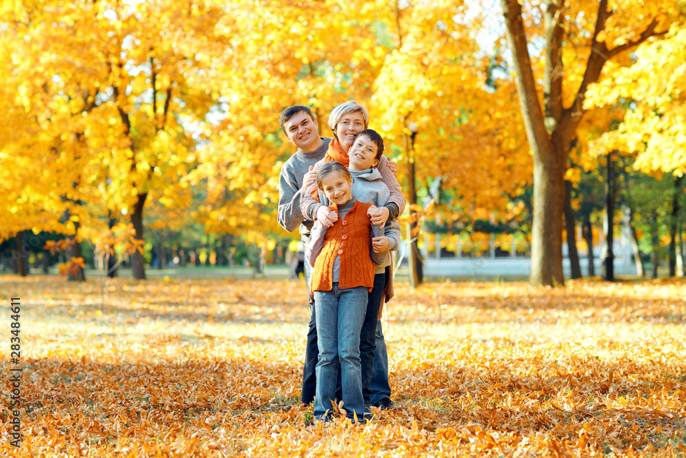 Happy family posing, playing and having fun in autumn city park. Children and parents together having a nice day. Bright sunlight and yellow leaves on trees, fall season. Happy family posing, playing and having fun in autumn city park. Children and parents together having a nice day. Bright sunlight and yellow leaves on trees, fall season.