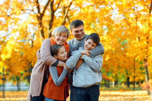 Happy family posing, playing and having fun in autumn city park. Children and parents together having a nice day. Bright sunlight and yellow leaves on trees, fall season. © soleg