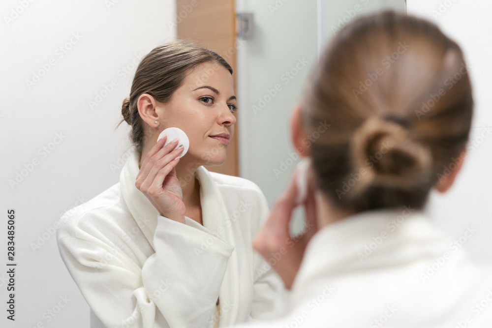 Woman in white bathrobe holding cotton pad in hands Woman in white bathrobe holding cotton pad in hands