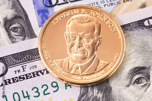 one dollar golden coin with Lyndon Baines Johnson portrait, and hundred dollars banknotes photo