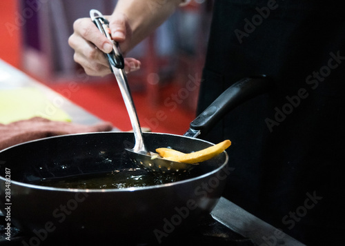 Chef is cooking french fries in the kitchen, Chef cooking fried potato in pan © NORN