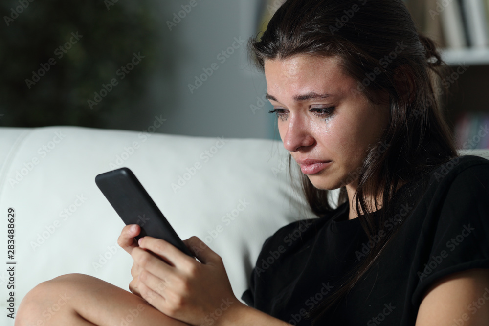 Sad teenager checking phone cyber bullying messages Sad teenager checking phone cyber bullying messages