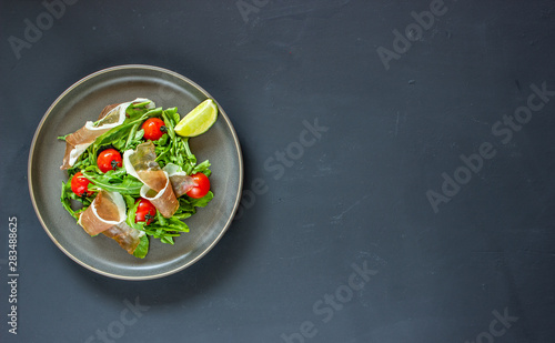 Salad with arugula, tomatoes and prosciutto. Italian cuisine. Healthy eating. Diet.