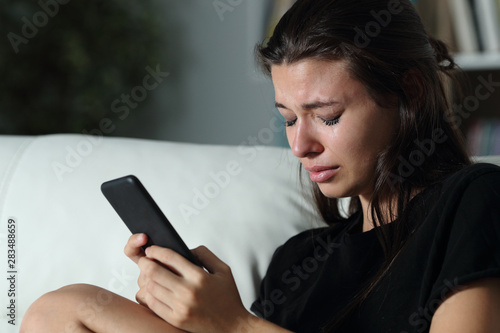 Fotografia Sad teen crying after read phone message