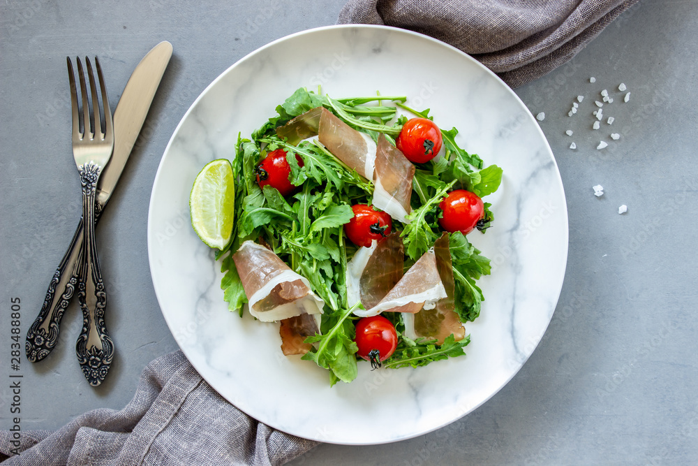 Salad with arugula, tomatoes and prosciutto. Italian cuisine. Healthy eating. Diet. Salad with arugula, tomatoes and prosciutto. Italian cuisine. Healthy eating. Diet.