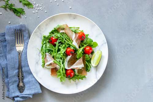 Salad with arugula, tomatoes and prosciutto. Italian cuisine. Healthy eating. Diet.