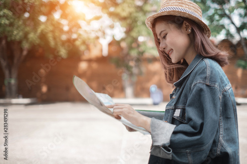 Smiling woman traveler in thapae gate landmark chiangmai thailand with backpack holding world map on holiday, relaxation concept, travel concept photo