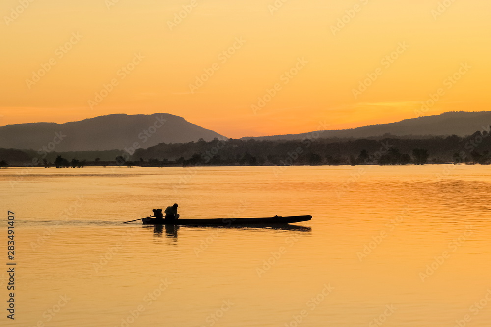 River view morning of a small fishing boat running in Mekong river with yellow sun light background, sunrise at Khong Chiam, Ubon Ratchathani, north-eastern of Thailand.