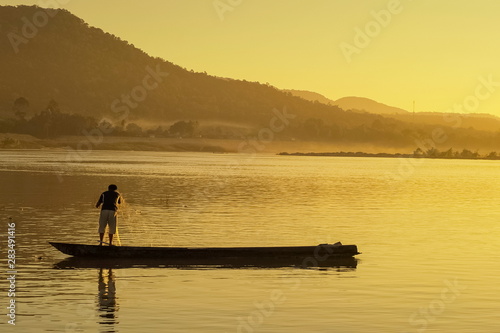 view of a fisherman floating a small boat in Mekong river with yellow sun light background  sunrise at Khong Chiam  Ubon Ratchathani  Thailand.